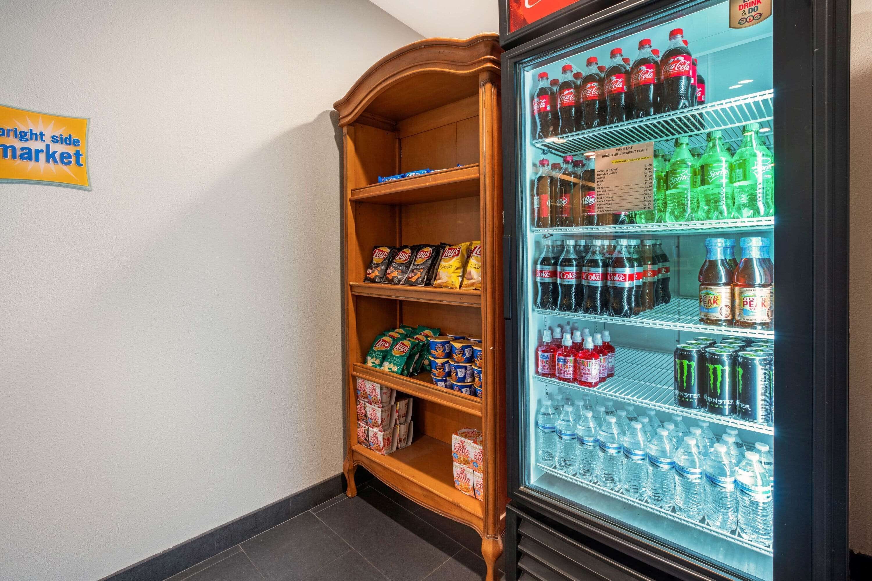 A vending machine stocked with beverages and snacks, and a wooden shelf unit with packaged goods.