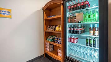 A vending machine stocked with beverages and snacks, and a wooden shelf unit with packaged goods.