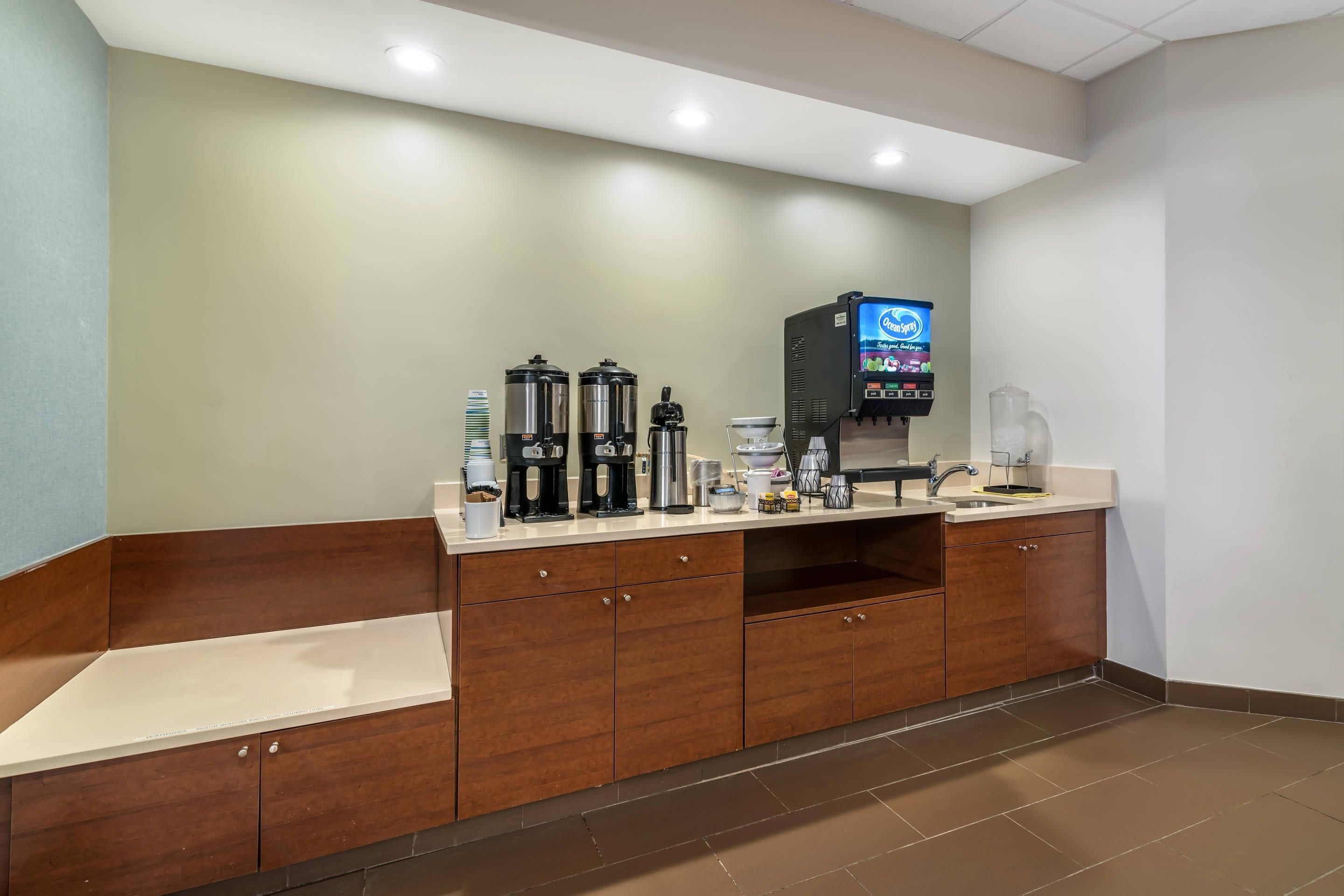 Ein Hotel-Empfangsbereich mit Kaffeestation, einem digitalen Bildschirm und einer Rezeption.