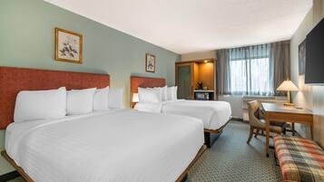 Quarto de hotel com duas camas, uma escrivaninha, uma cadeira, televisão e janela com cortinas.