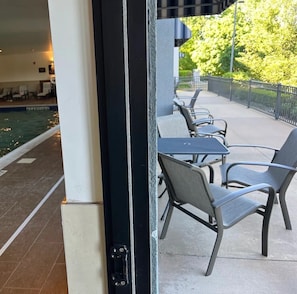 An outdoor seating area with tables and chairs, a pool, and a view of greenery. - The Clocktower Hotel Latham - North Albany, an Ascend Collection Hotel (Cohoes)