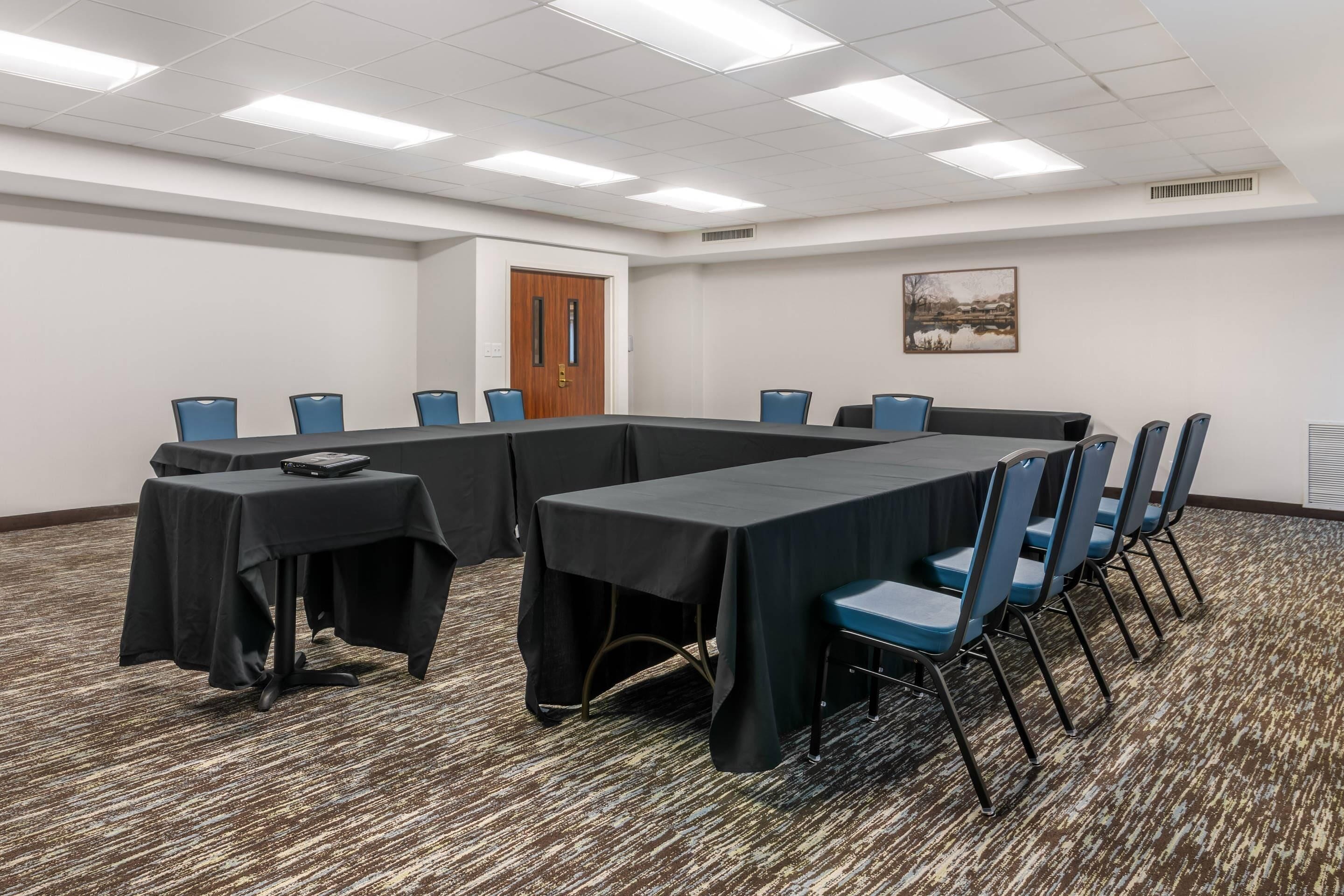 A conference room with a long table, blue chairs, and a carpeted floor.