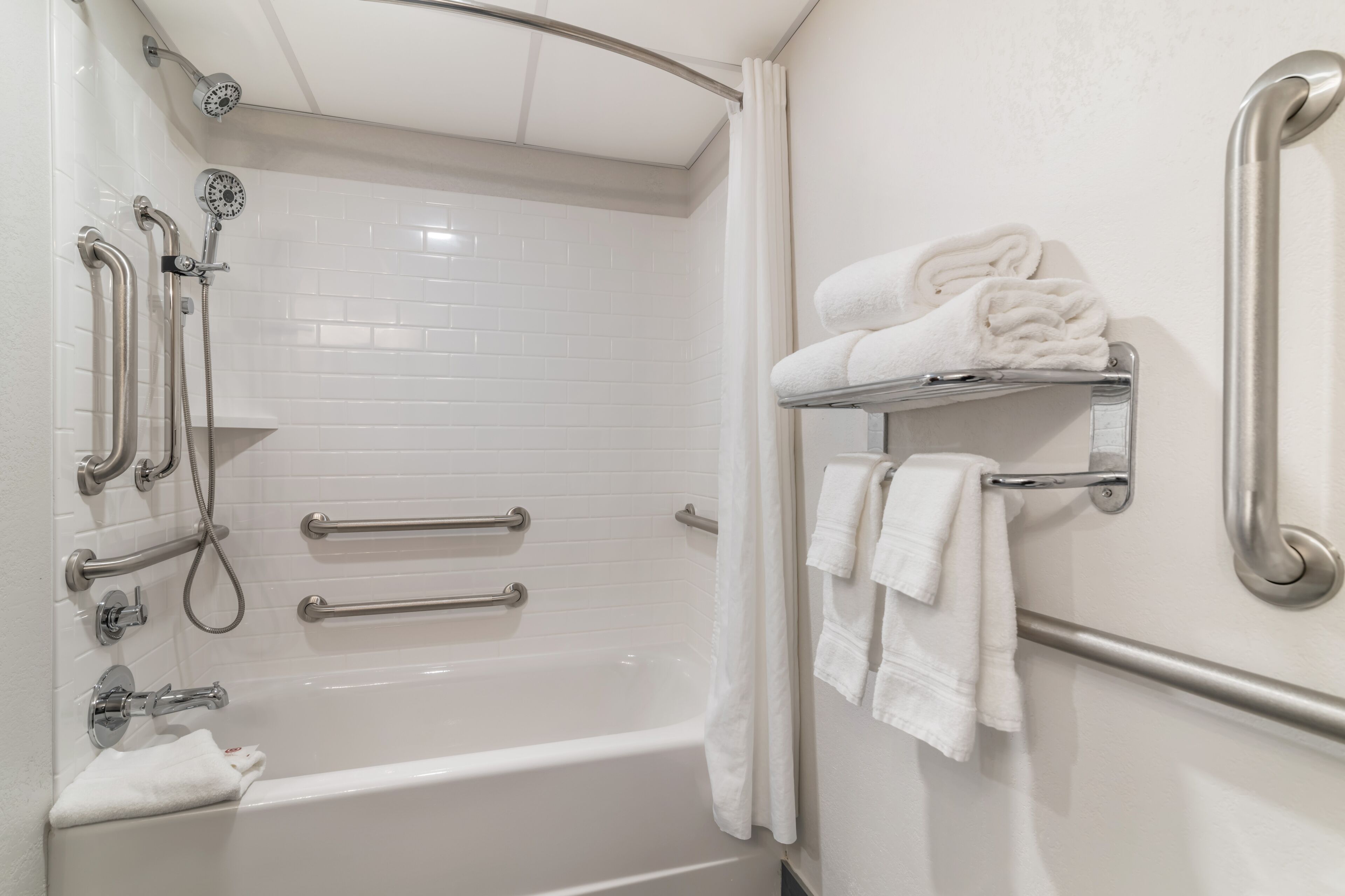Un bagno dotato di vasca, maniglie, soffione della doccia e portasci.