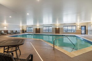 An indoor swimming pool with clear water, surrounded by lounge chairs and a table. - The Clocktower Hotel Latham - North Albany, an Ascend Collection Hotel (Cohoes)