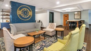Un hall d’hôtel moderne, doté d’une grande horloge murale, d’un espace salon et d’un espace repas.