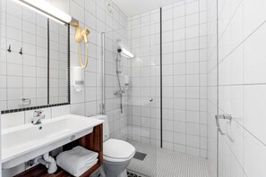 Ein modernes Badezimmer mit Waschbecken, Toilette und Duschbereich in Weiß.
