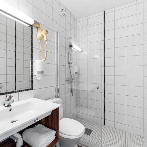Ein modernes Badezimmer mit Waschbecken, Toilette und Duschbereich in Weiß.