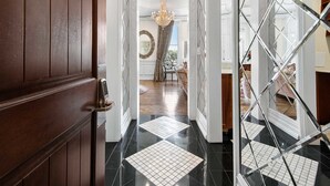 A hallway with a wooden door, black and white tiled flooring, and a mirrored wall. - Fairmount Hotel (San Antonio)