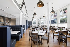 A spacious restaurant with high ceilings, large windows, and modern pendant lighting. - Fairmount Hotel (San Antonio)