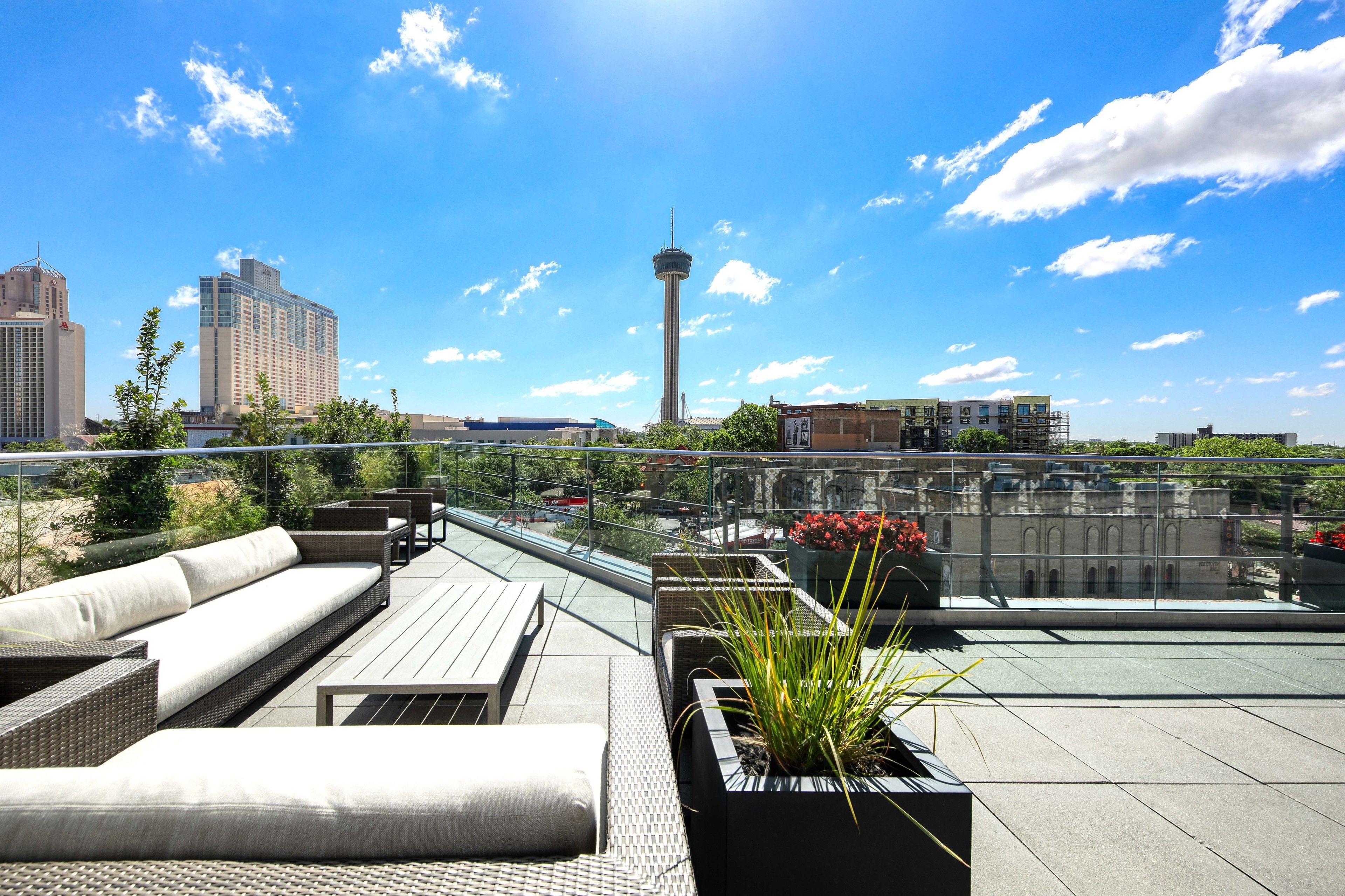 Een terras op het dak met buitenmeubilair, planten in potten en uitzicht op de skyline van de stad.