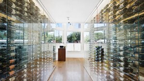 A wine cellar with glass walls and shelves filled with wine bottles. - Fairmount Hotel (San Antonio)