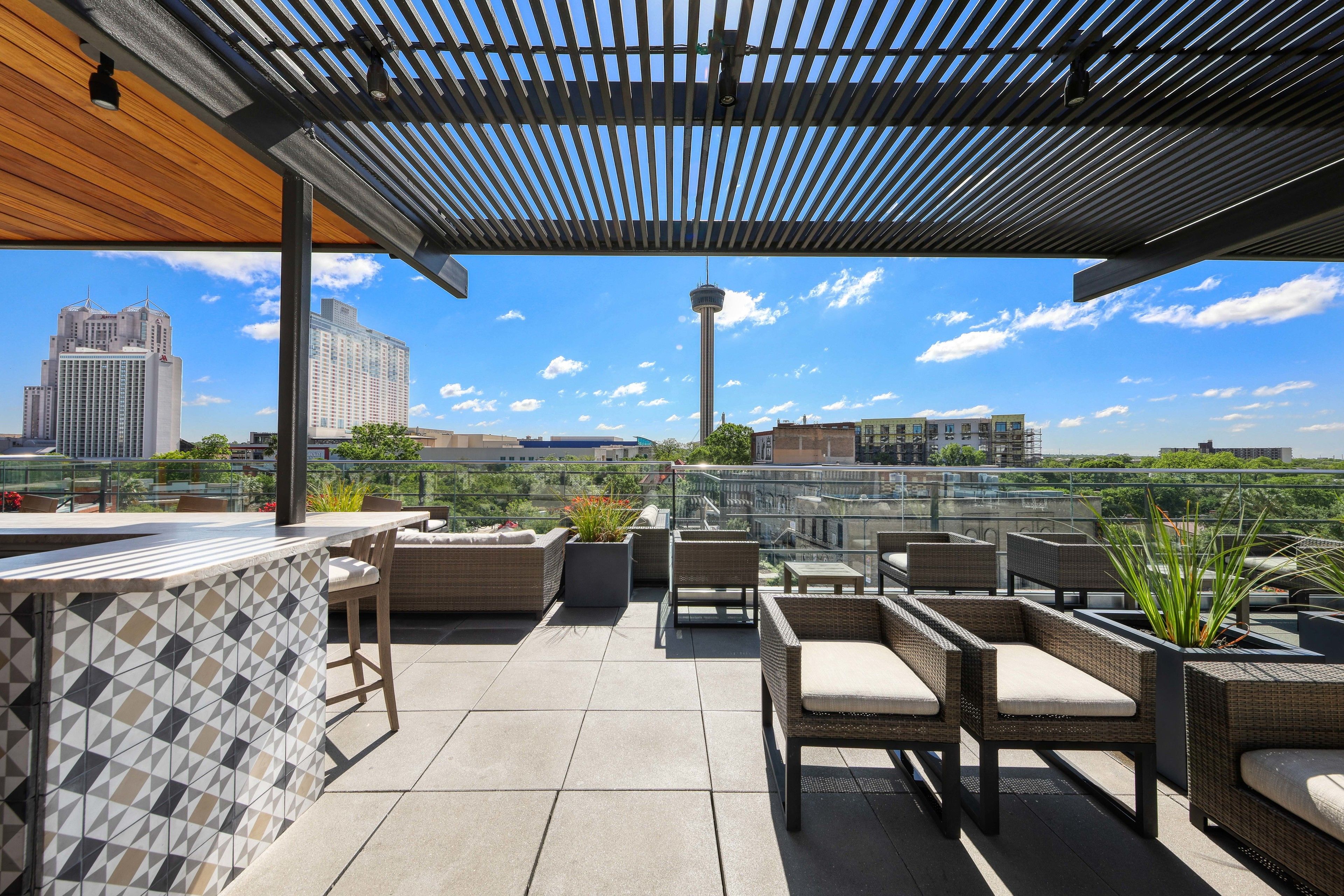 Eine Dachterrasse mit Sitzgelegenheiten im Freien, einer Bar und Blick auf die Stadtlandschaft.