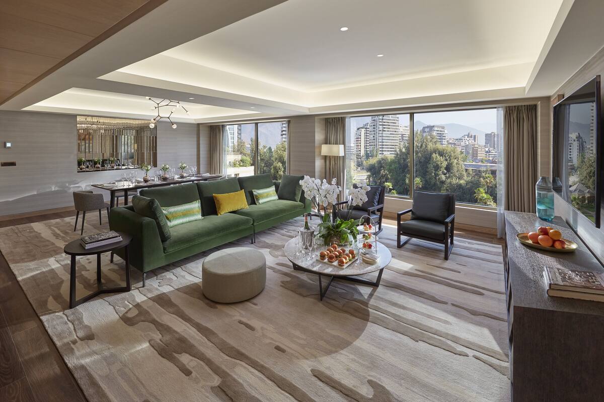A modern living room with a green sofa, a round coffee table, and a city view.