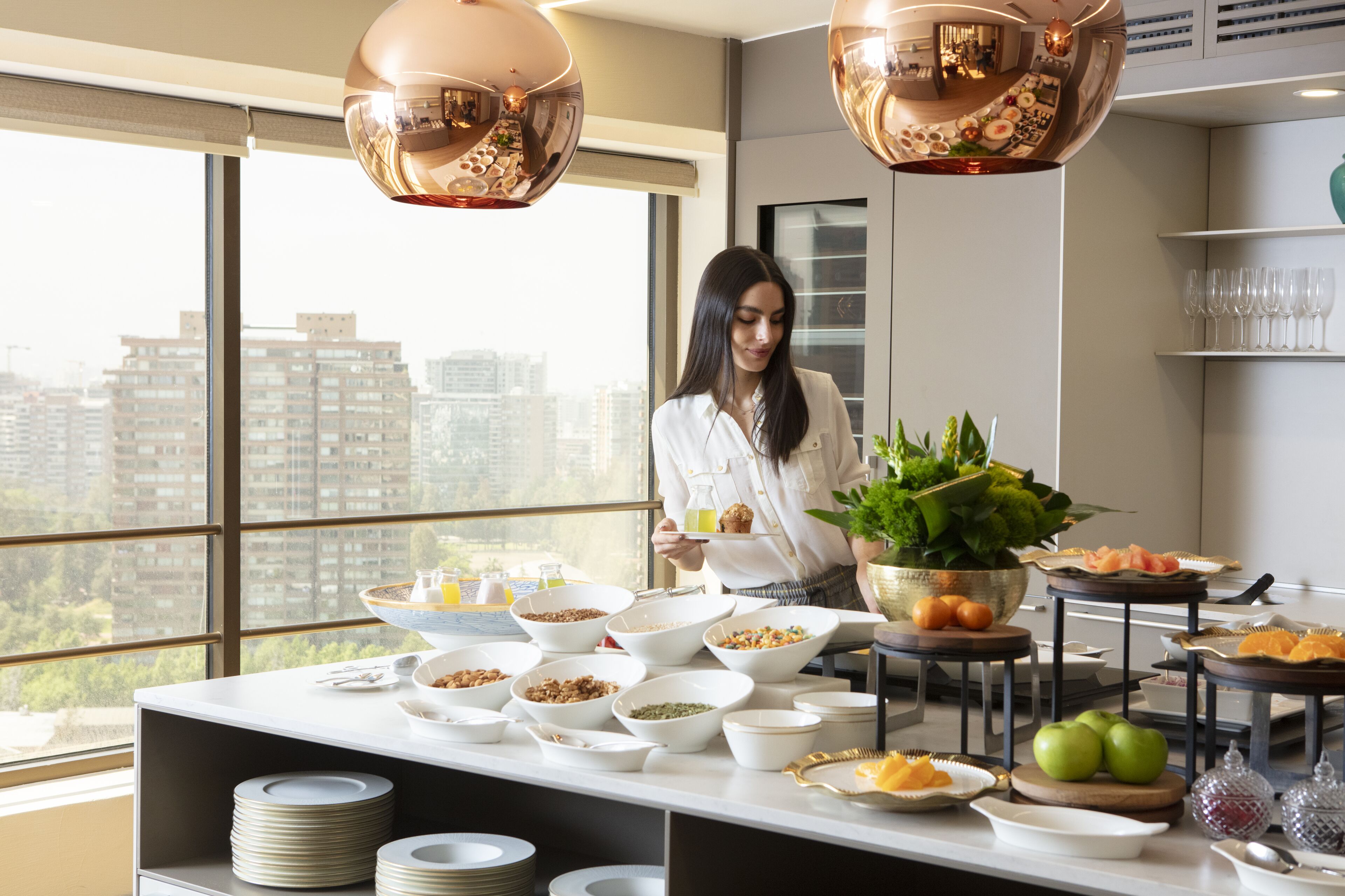 Um buffet de café da manhã com diversas opções de alimentos e vista para a cidade.