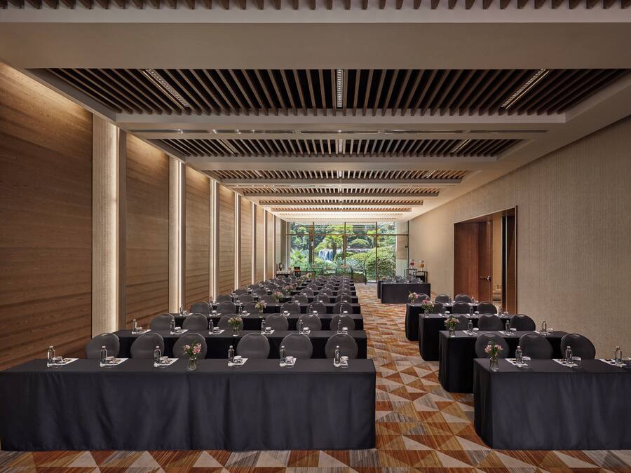 A conference room with rows of tables, chairs, and a view of a waterfall through large windows.