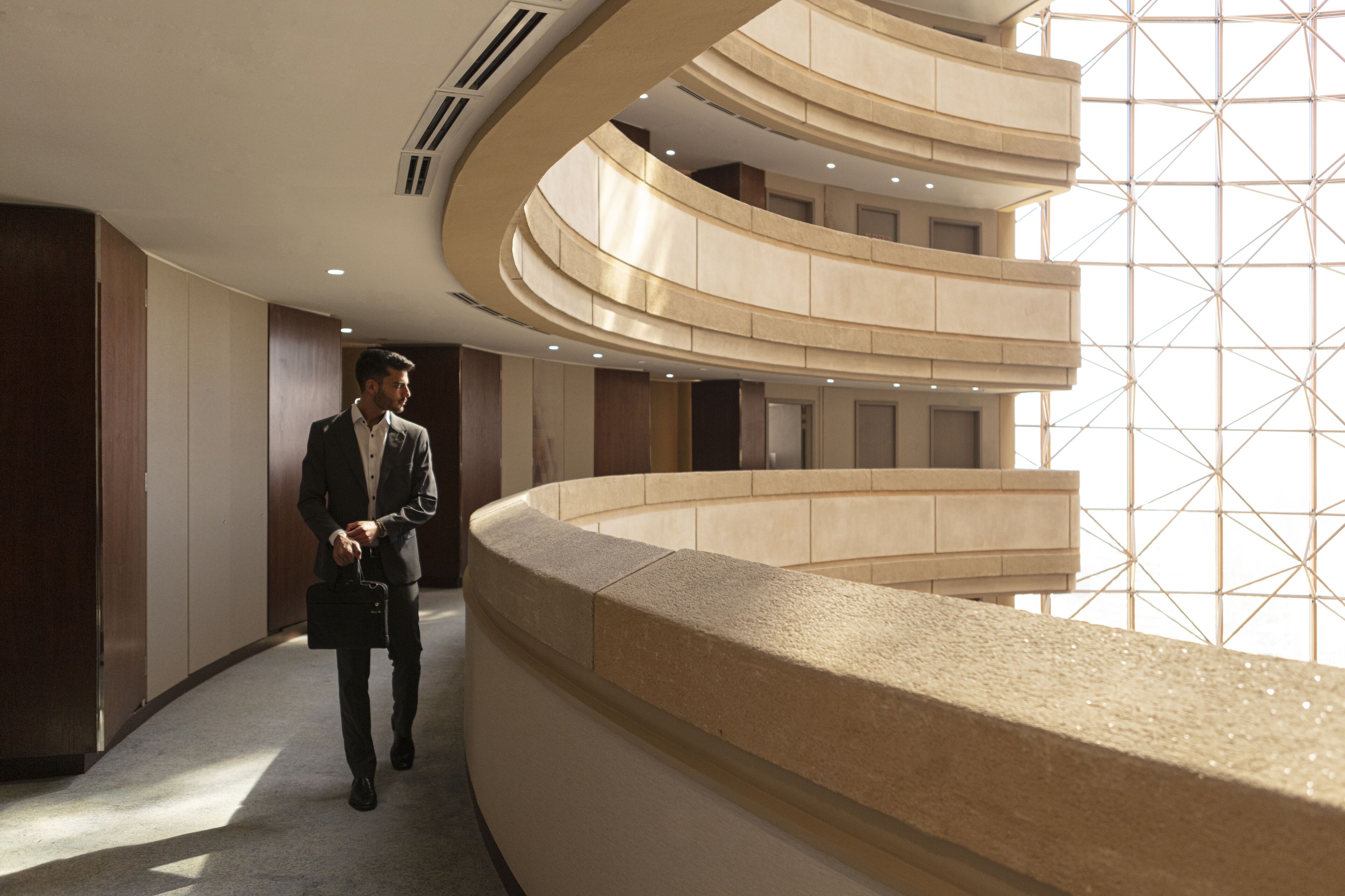 A modern hotel interior with a curved reception desk, a spiral staircase, and a geometric glass wall.