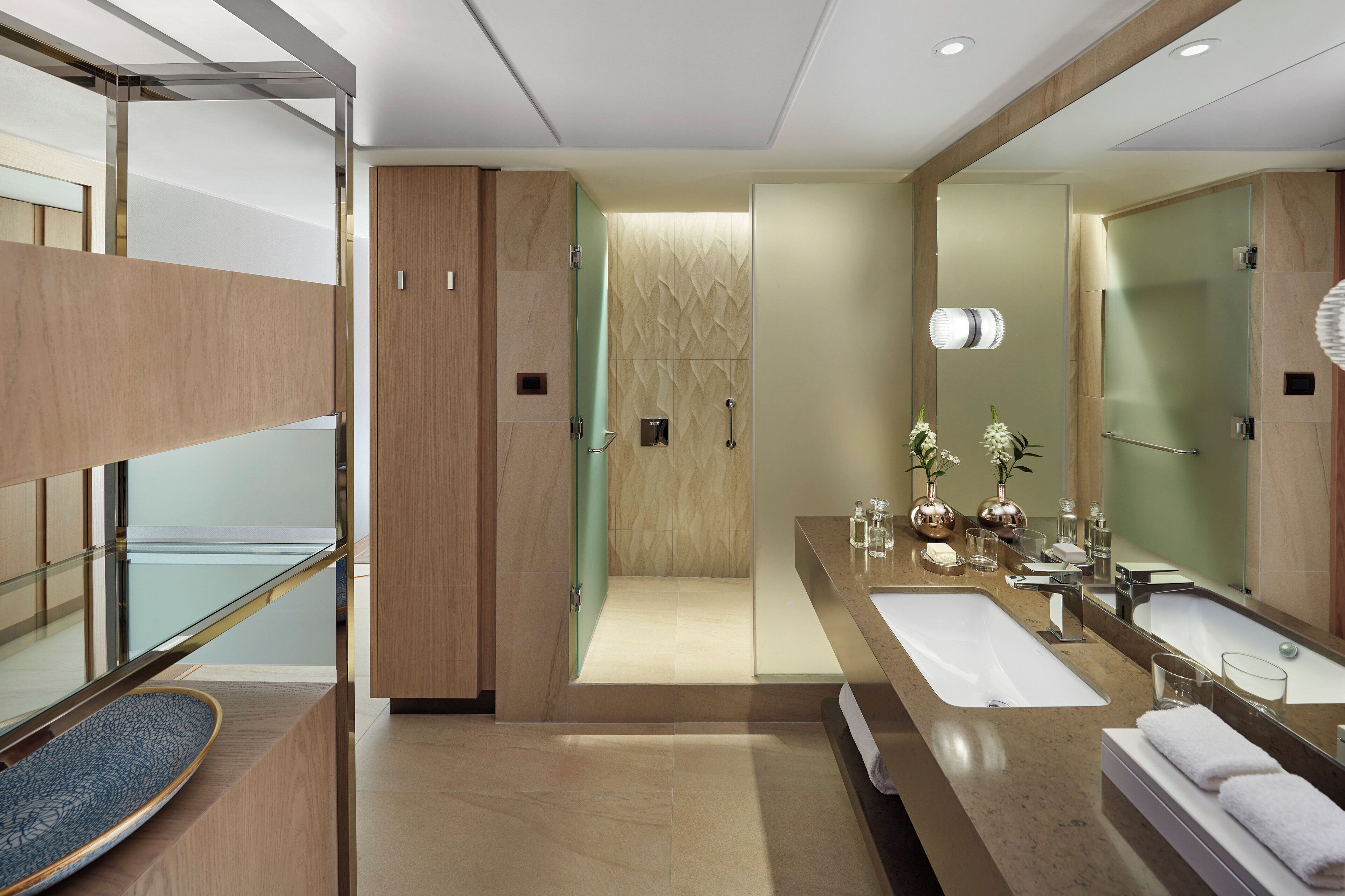 A modern bathroom with a large mirror, two sinks, a shower, and a glass-enclosed balcony.