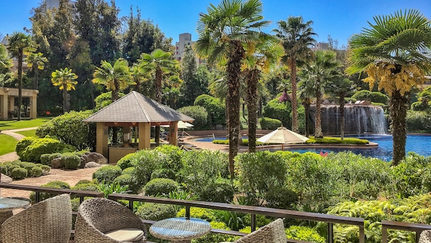 Un resort con piscina, palmeras, un pabellón y mobiliario para exteriores.