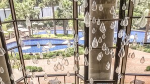Un área de estar moderna al aire libre con vistas a la piscina, que cuenta con muebles contemporáneos y elementos decorativos de vidrio.