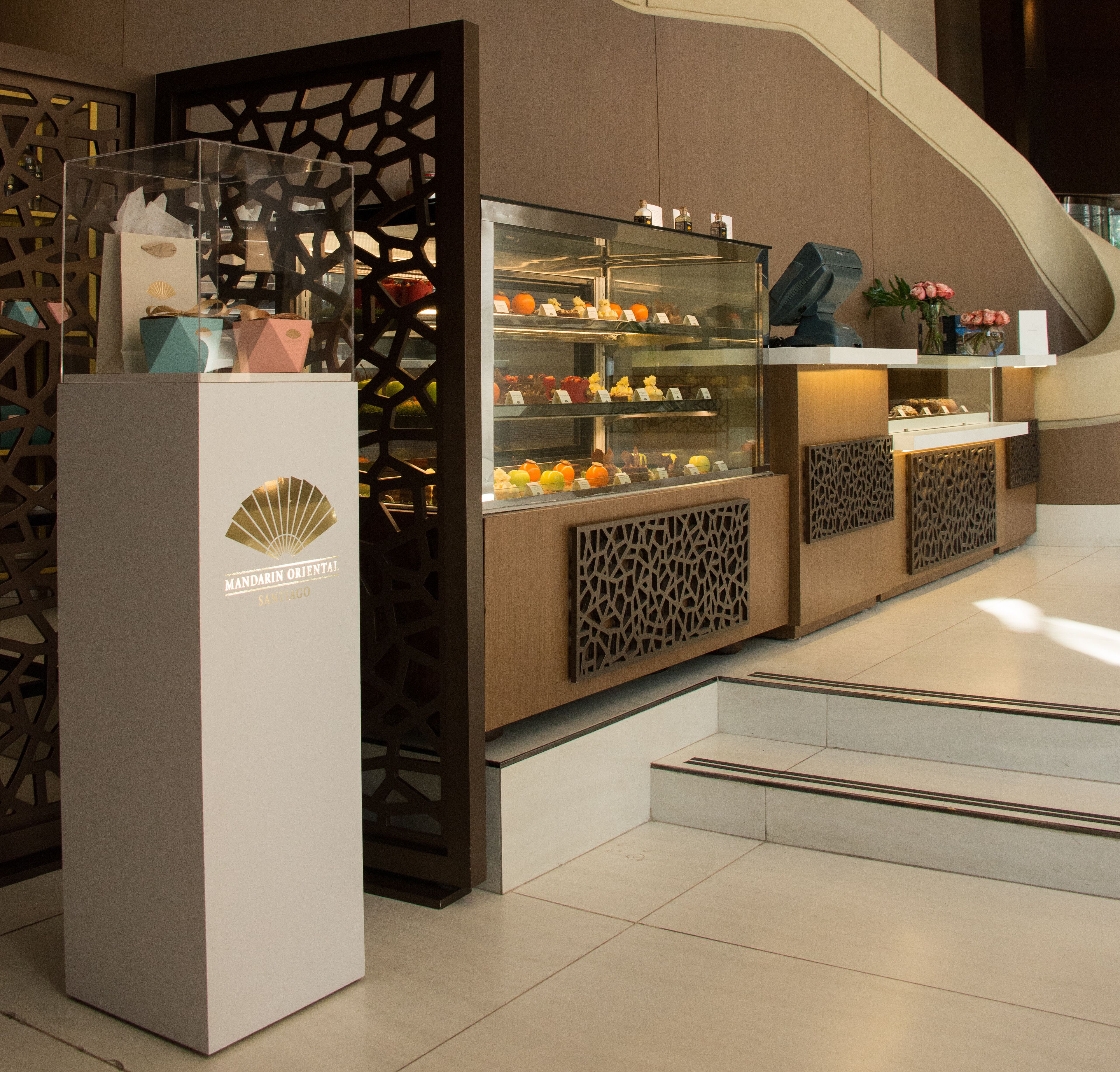 Un hall d’hôtel moderne agrémenté d’une cloison décorative en bois, d’une vitrine exposant divers objets et d’une enseigne indiquant « MANDARIN ORIENTAL ».