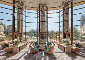 A spacious lobby with a modern design, featuring a large seating area, a central fireplace, and a view of the outdoor garden and pool area. - Mandarin Oriental, Santiago (Santiago)