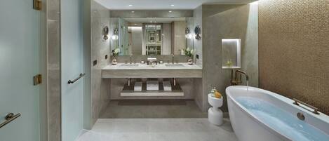 A modern bathroom with a large bathtub, a double sink vanity, and a walk-in shower.