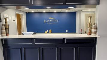 A reception desk with a blue wall, a Baymont logo, and two decorative vases.