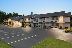 A motel with a parking lot, multiple rooms, and a small garden area. - Baymont by Wyndham Branford/New Haven (Branford)