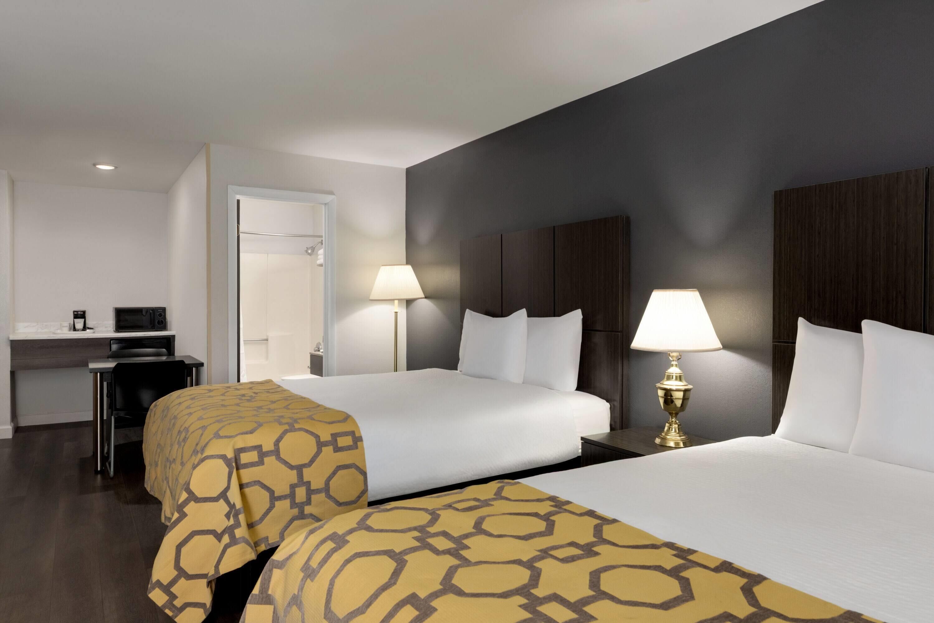 Quarto de hotel com duas camas, uma secretária e uma televisão.