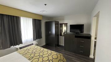 A hotel room with a bed, a television, a wardrobe, and a mirror.