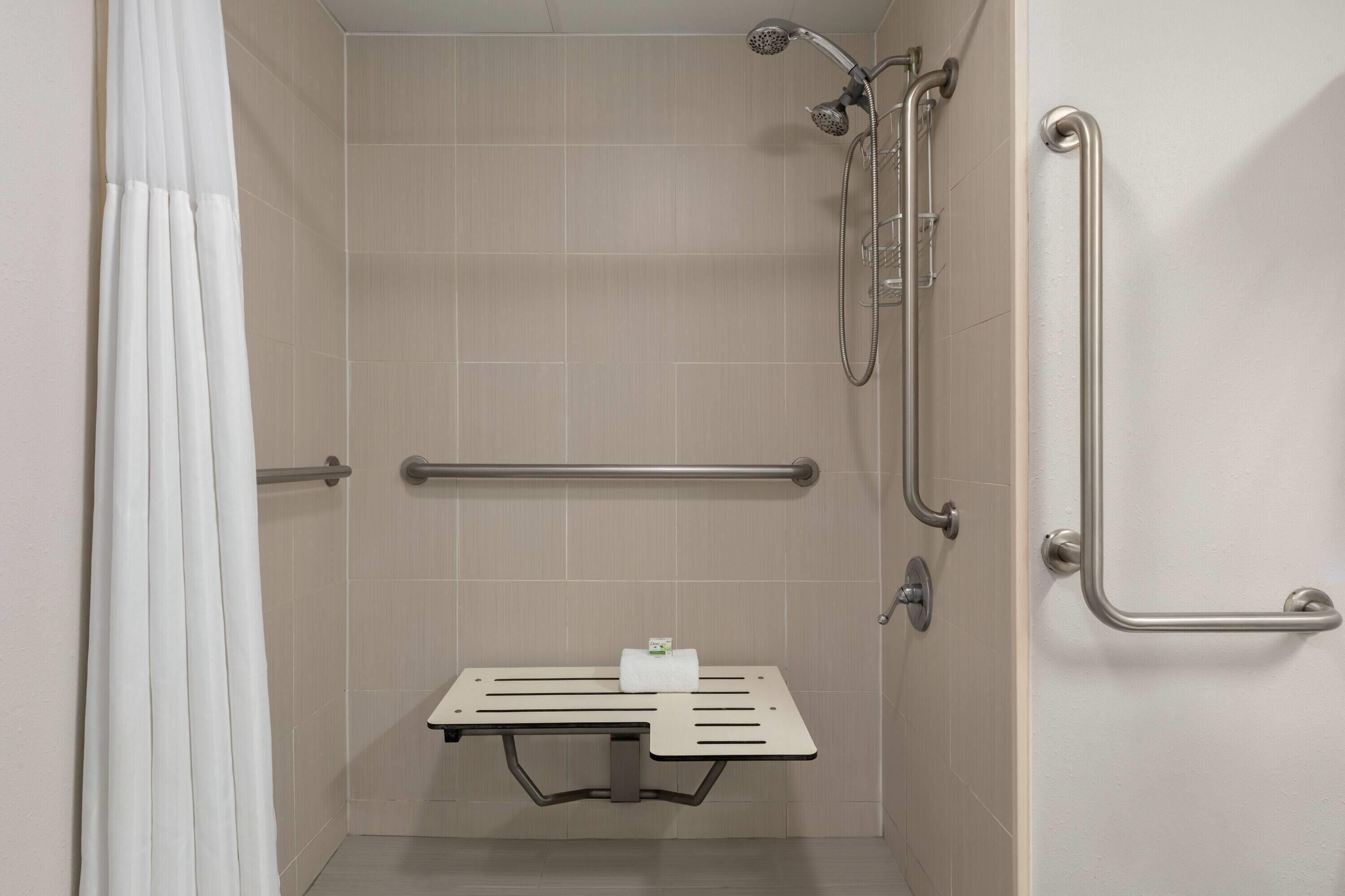 A shower area with a grab bar, a bench, and a towel rack.