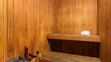 Una sauna con paredes y bancos de madera, un perchero y un estante con toallas.