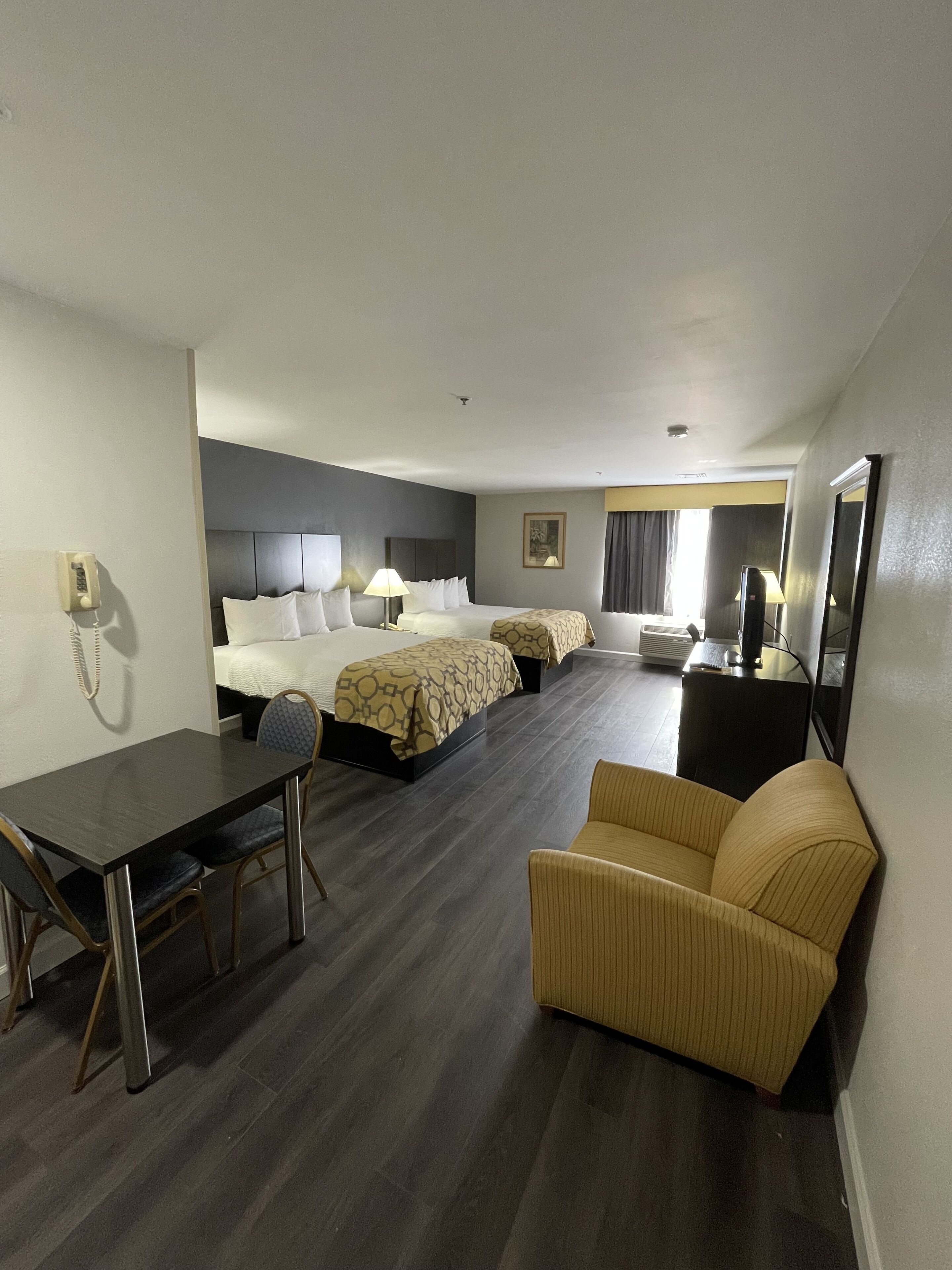 Habitación de hotel con dos camas, un escritorio, una silla, un sofá y un televisor.
