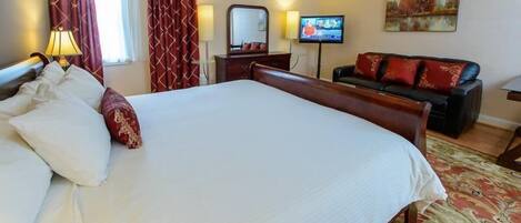 Una habitación de hotel con una cama grande, un sofá, un televisor y un cuadro en la pared.