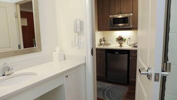 A modern bathroom with a white vanity, a large mirror, and a built-in microwave above the sink.