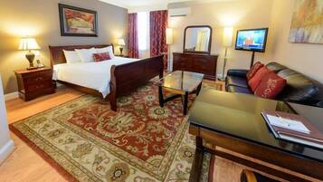 Una habitación de hotel con cama, escritorio, televisor, cómoda y una alfombra grande.