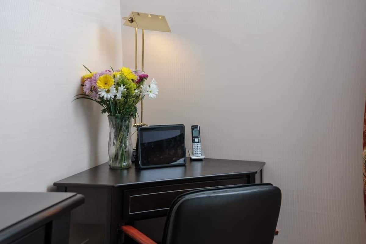 A desk with a vase of flowers, a microwave, and a telephone.