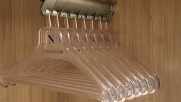 A clear plastic hanger rack with a letter 'N' on one of the hangers, mounted on a wall with a wooden panel background.