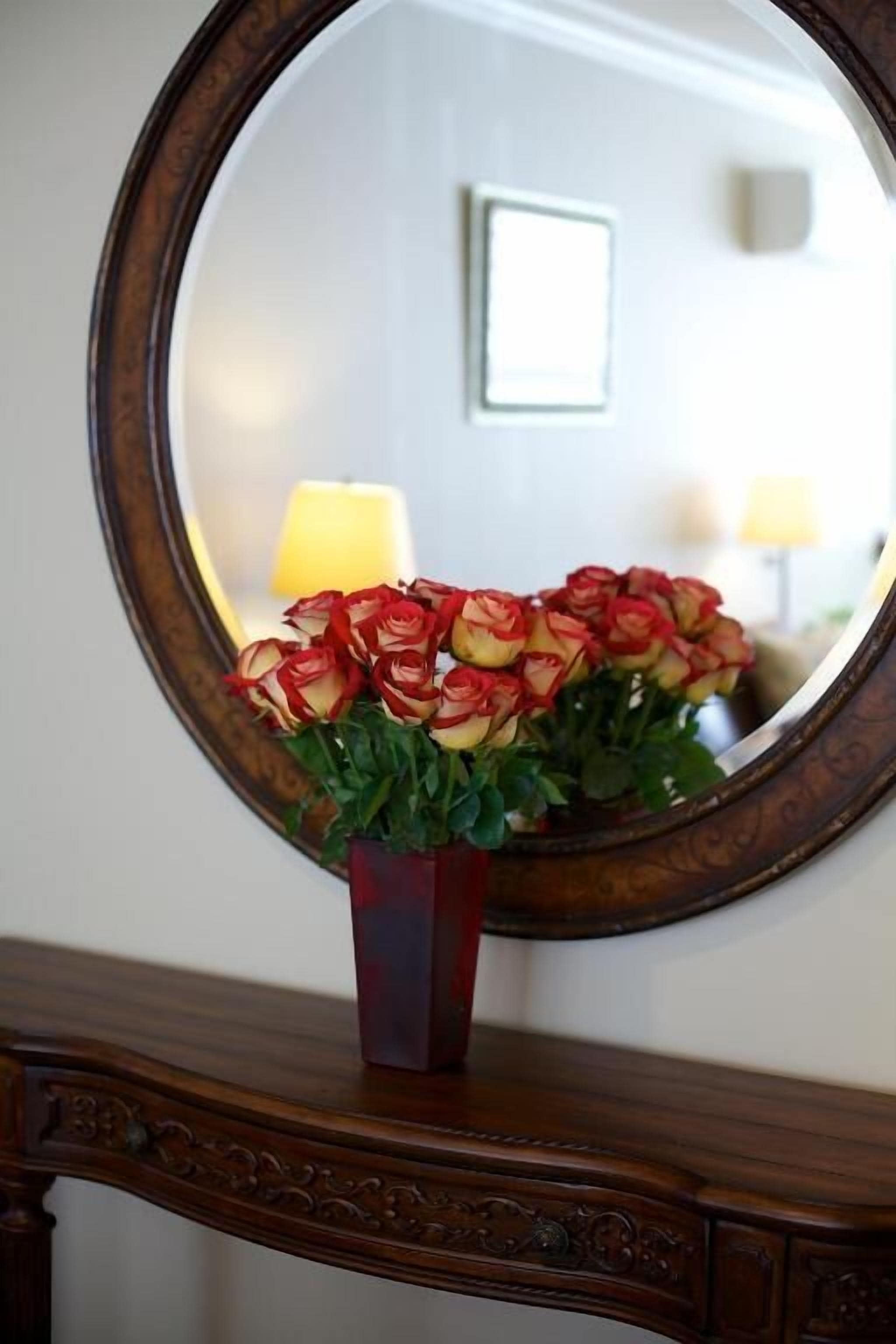 A mirror with a floral arrangement in a vase.