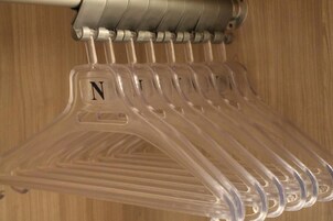 A set of transparent plastic hangers with a letter 'N' on them, hanging on a metal rod.
