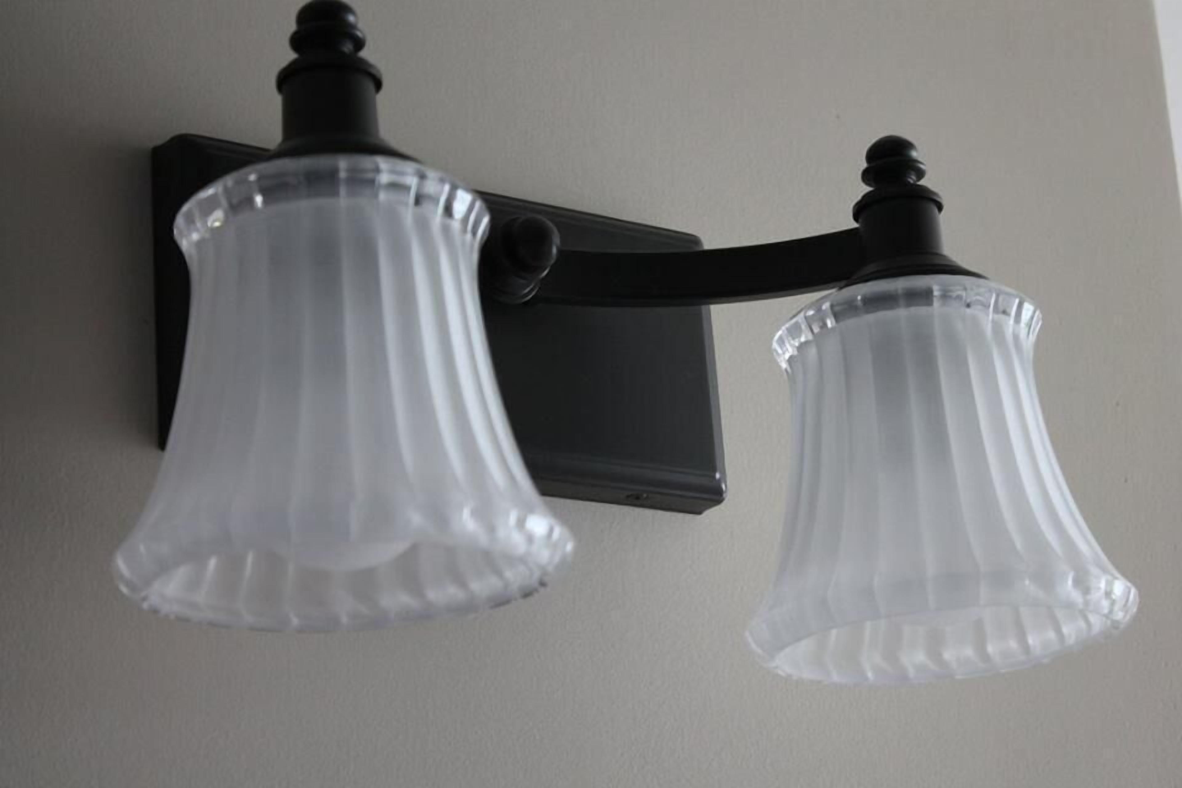 Two wall-mounted light fixtures with clear glass shades and black fixtures.