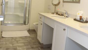 A bathroom with a shower, toilet, sink, and mirror.