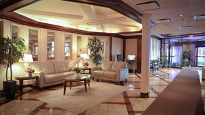 A spacious lobby with a curved ceiling, two sofas, a coffee table, and potted plants.