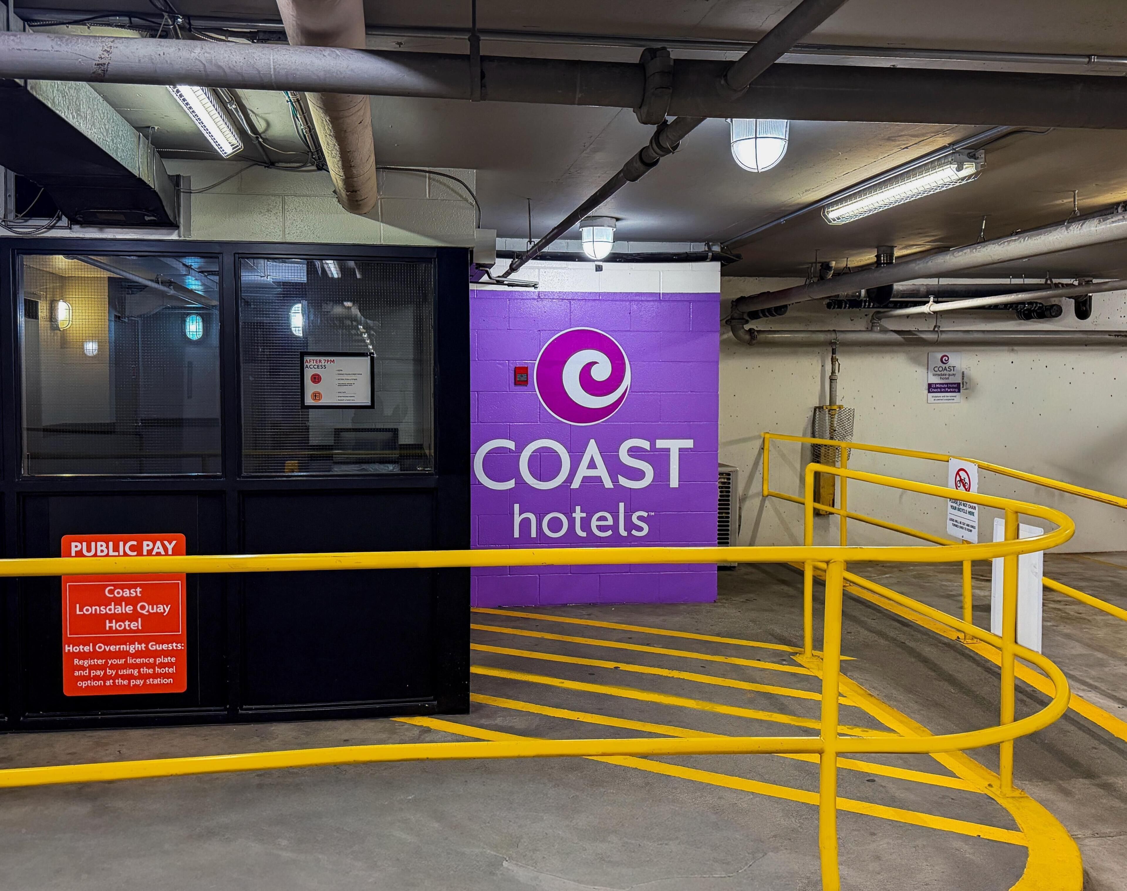 Una estación de pago público con un letrero de 'Coast Hotels', un letrero de 'Public Pay' y un letrero de 'Coast Lonsdale Quay Hotel'.