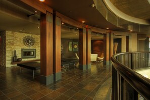 Relax in the inviting lobby, featuring a cozy fireplace, comfortable seating, and a striking circular art piece.
