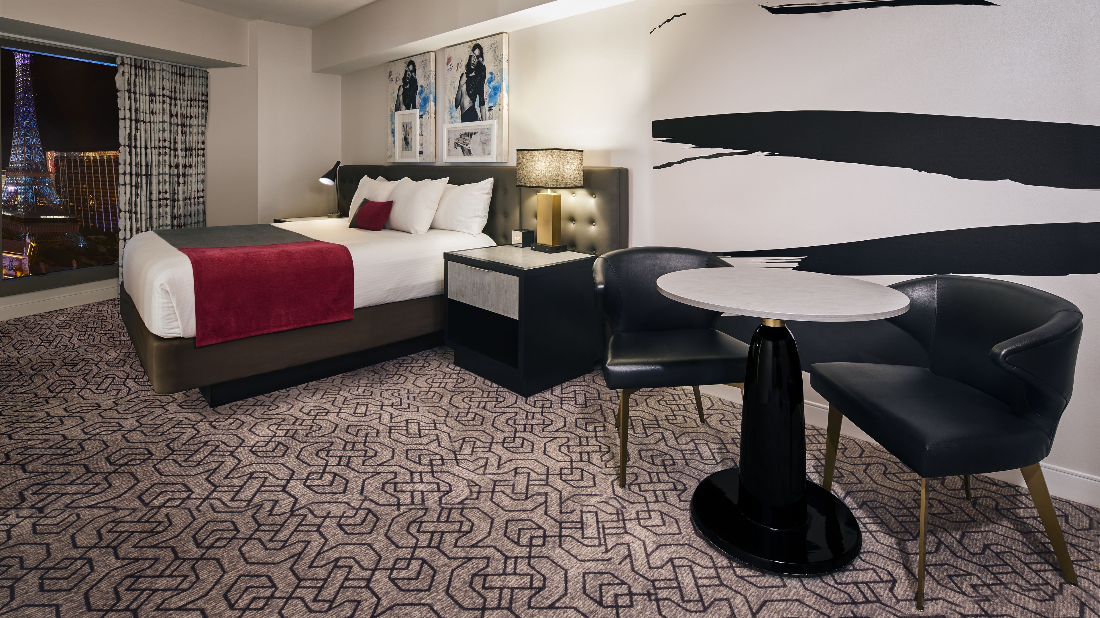 Ein Hotelzimmer mit einem Bett, einem Nachttisch, einer Lampe und einem runden Tisch mit Stühlen.