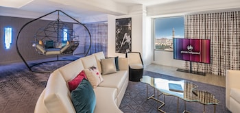 A modern living room with a large window offering a city view, a sofa set, and a coffee table. at Planet Hollywood Resort & Casino