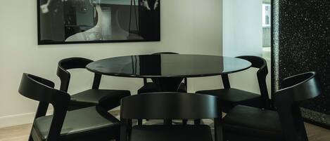 A modern dining area with a round table, six black chairs, and a unique geometric patterned floor.