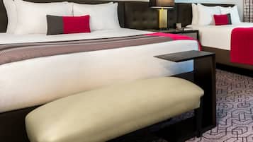 A hotel room with a large bed, a bedside table, a chair, and a patterned carpet.
