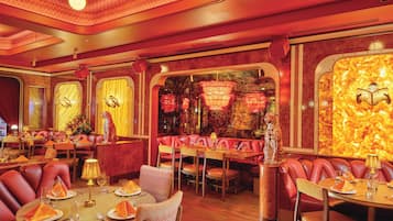 Un restaurante con asientos de cuero rojo, mesas redondas y una decoración interior cálida con tonos rojos.